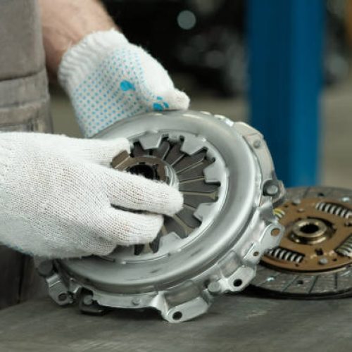 A new clutch kit is in the hands of an auto mechanic. Control of the serviceability of the leading, driven and exhaust bearings.